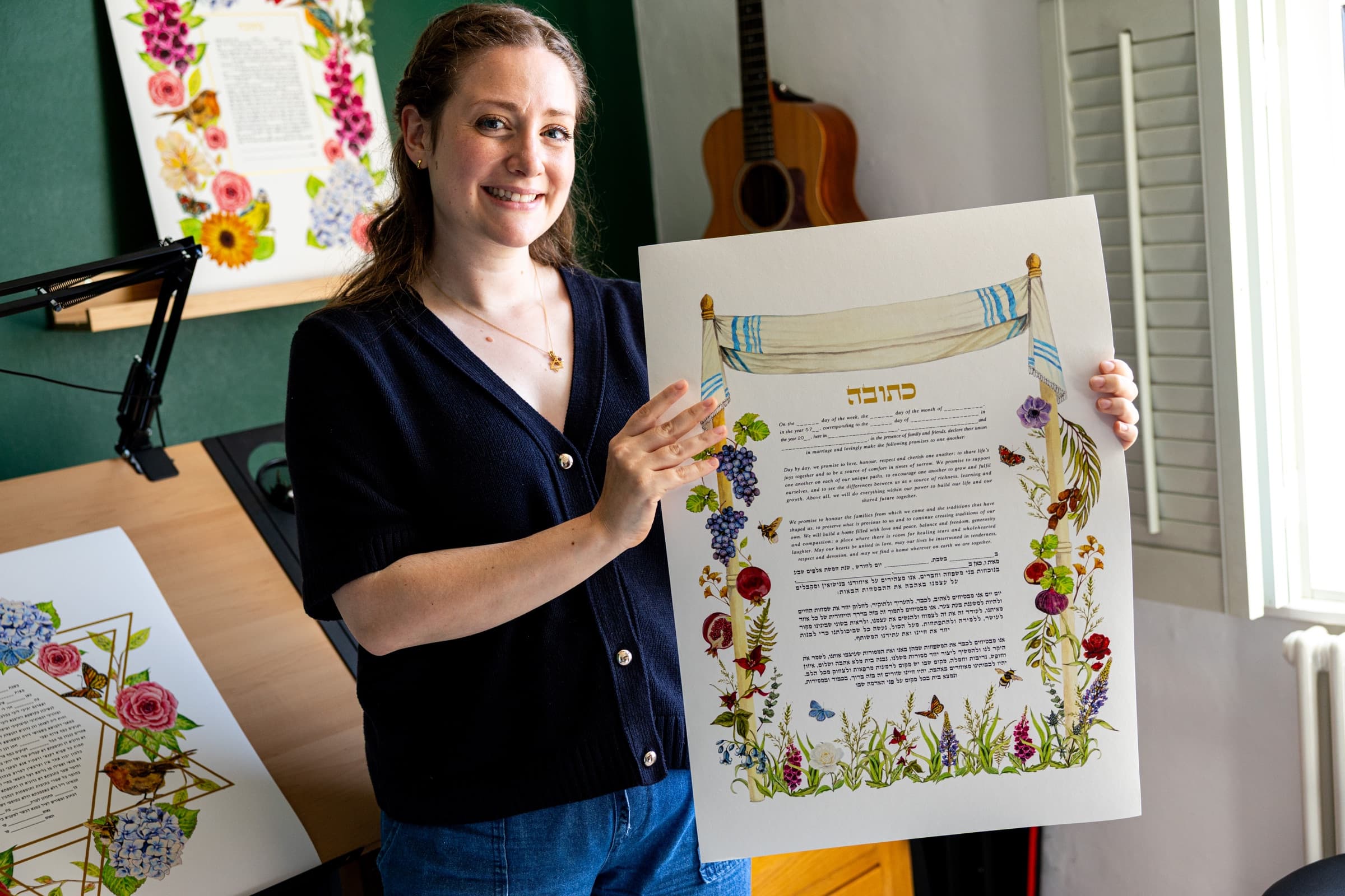 Sophie Bacall holding a hand-painted Seven Species Meadow ketubah